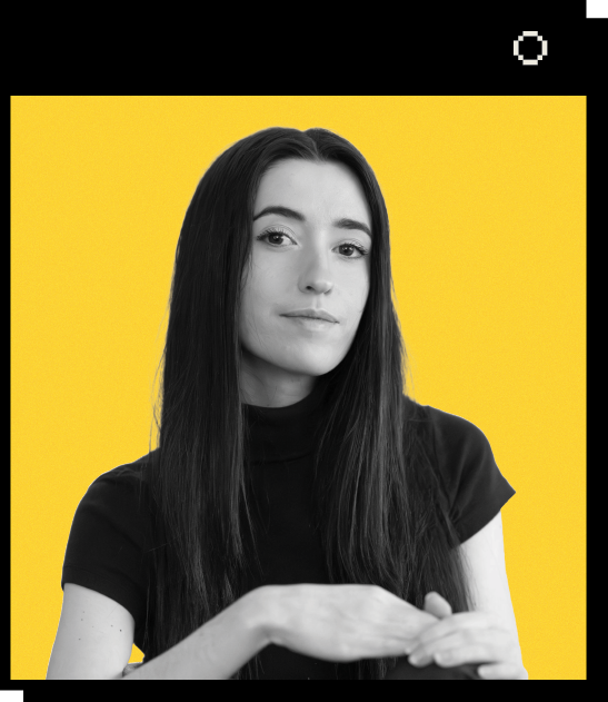 Headshot of Julia Martinez against a yellow background. Julia has long dark hair and is wearing a black high-neck top, looking directly at the camera with a neutral expression.