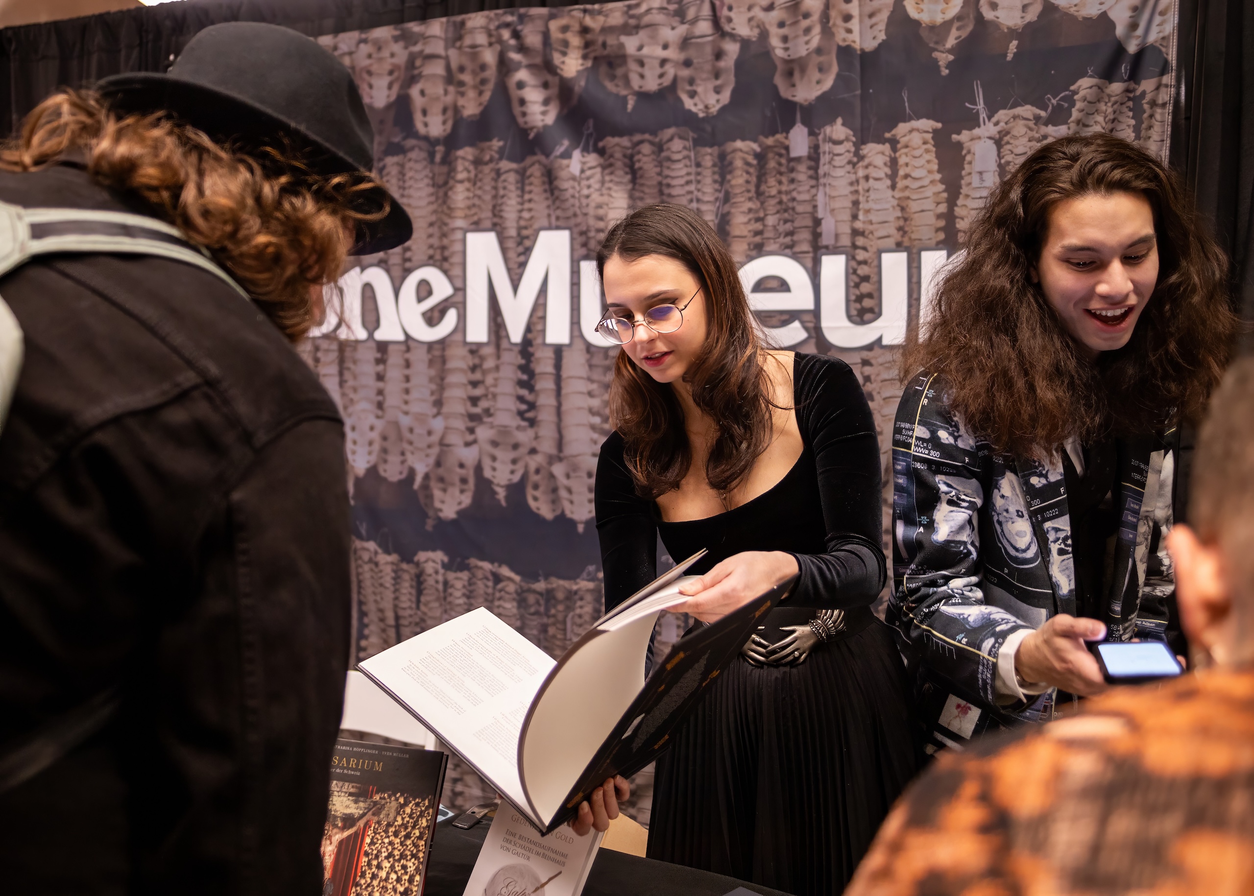 In a conference booth for The Bone Museum, Masha Potemkin holds out an open book to a visitor.