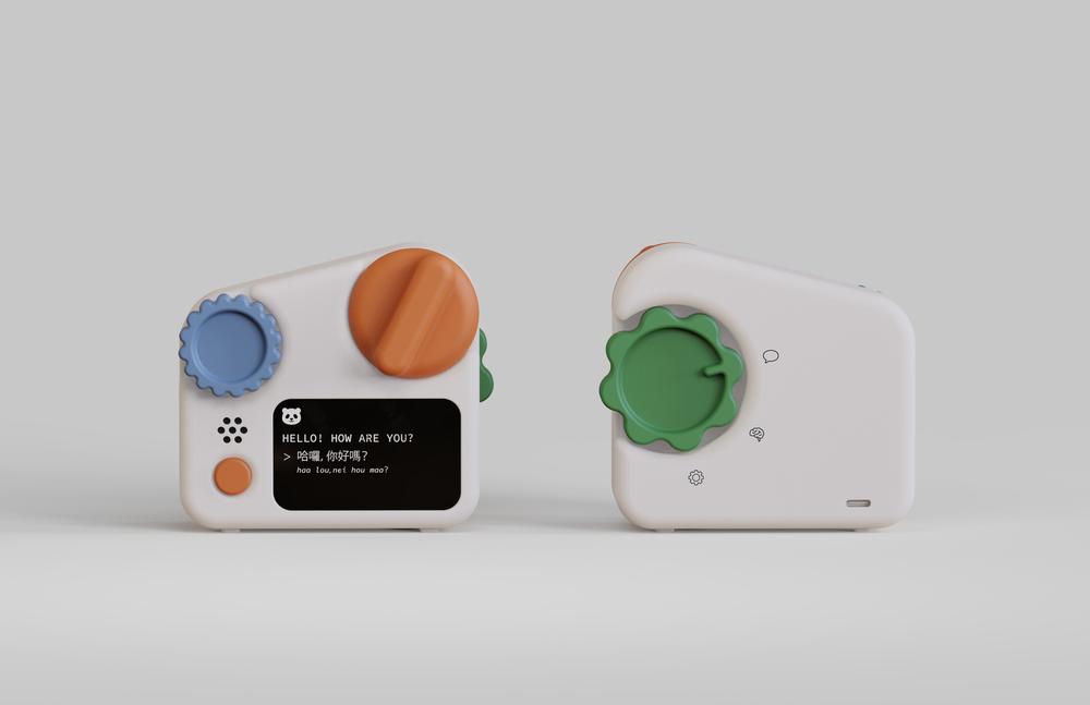 A compact, white electronic device resembling a camera or toy, featuring colorful buttons and knobs. The front has a blue and orange circular controls, a small screen displaying text, and a speaker area. The back view shows a green flower-shaped knob and several small symbols. The overall design is playful and modern, set against a light gray background.