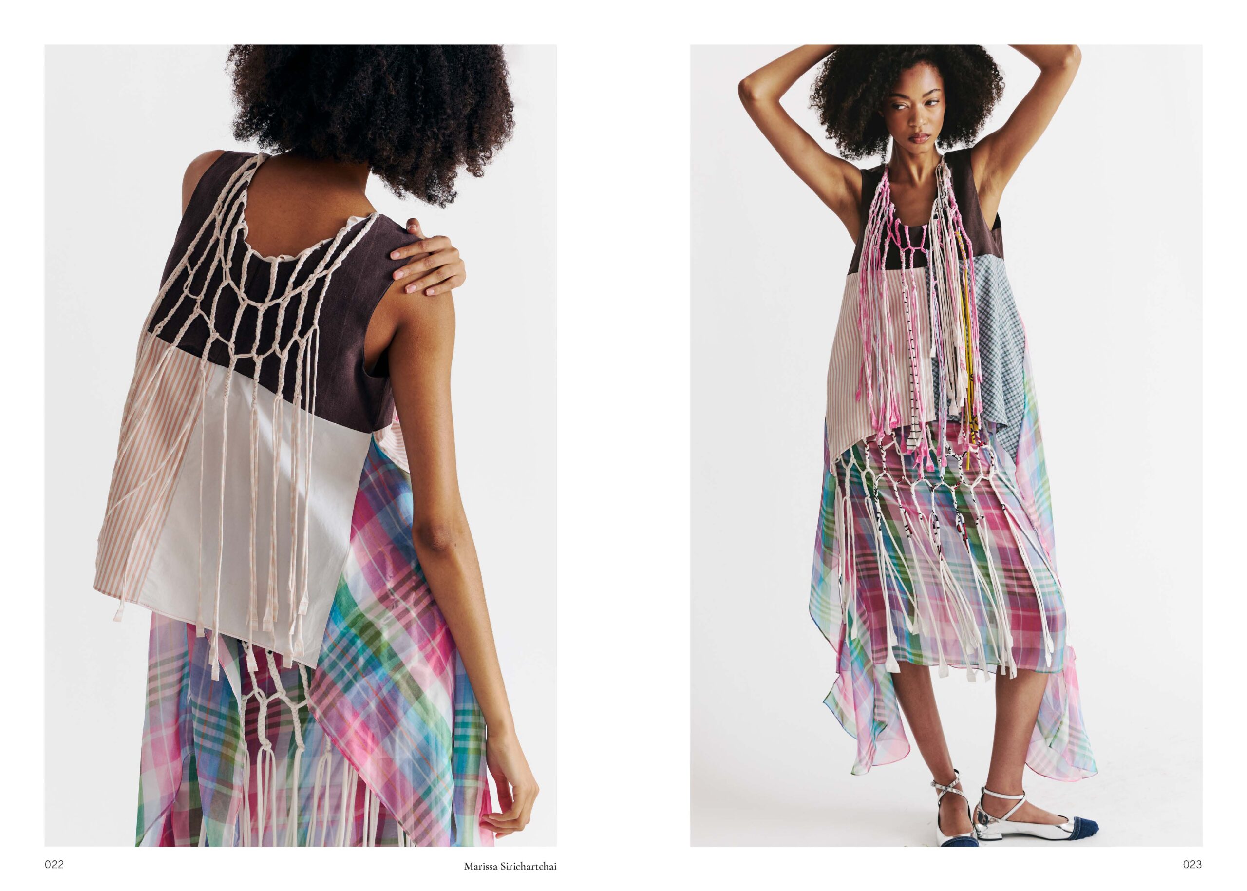 A model poses in a unique, colorful dress featuring a mix of fabrics, including plaid and solid colors. The dress has an asymmetrical hem and intricate knot detailing at the back. The model's natural, curly hair adds to the artistic presentation of the outfit, which combines various textures and layers. The background is minimal, emphasizing the design of the dress.