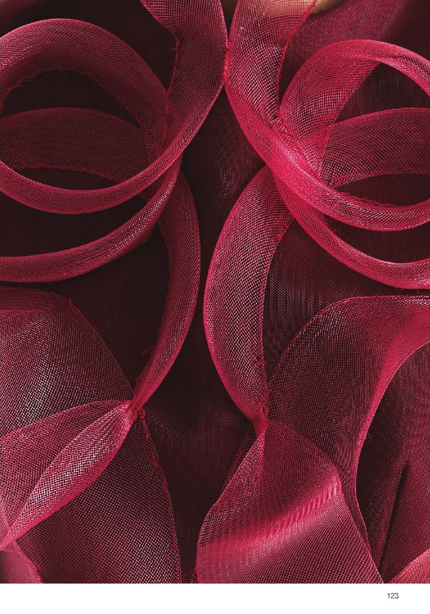 Close-up of vibrant magenta fabric with sheer, wavy layers forming a textured design. The layers create a dynamic, flowing pattern against a dark background, showcasing the intricate details of the material's texture and structure.
