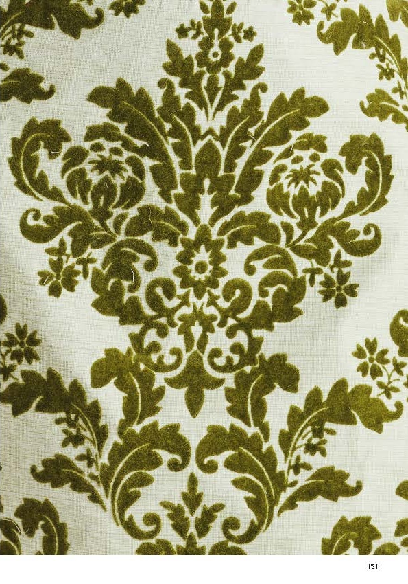 A close-up view of a fabric featuring an ornate damask pattern. The design is predominantly in shades of dark green against a light, neutral background. The intricate floral and foliage motifs are symmetrical and create a rich, textured appearance.