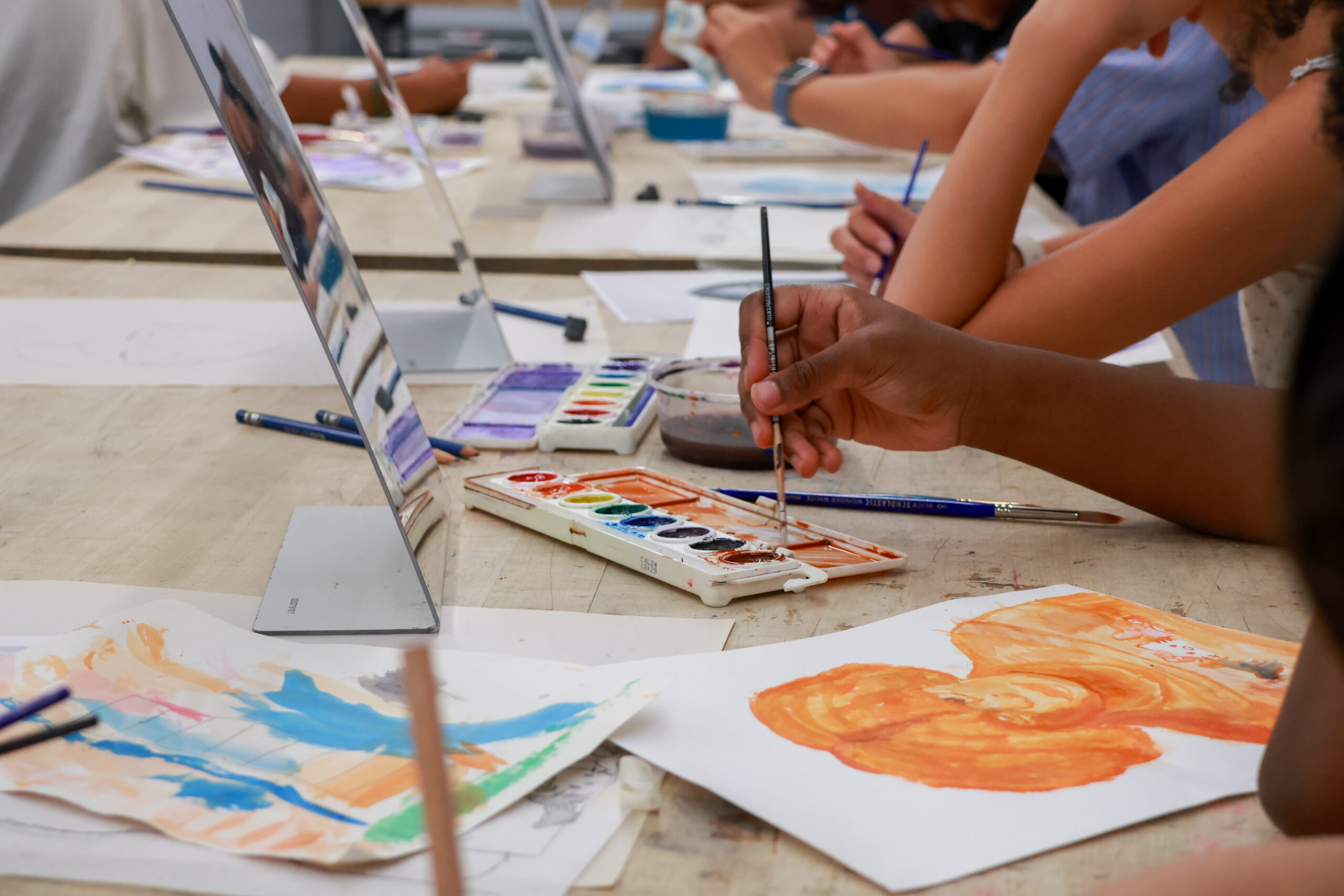 A close-up view of a creative workspace with several people engaged in painting.