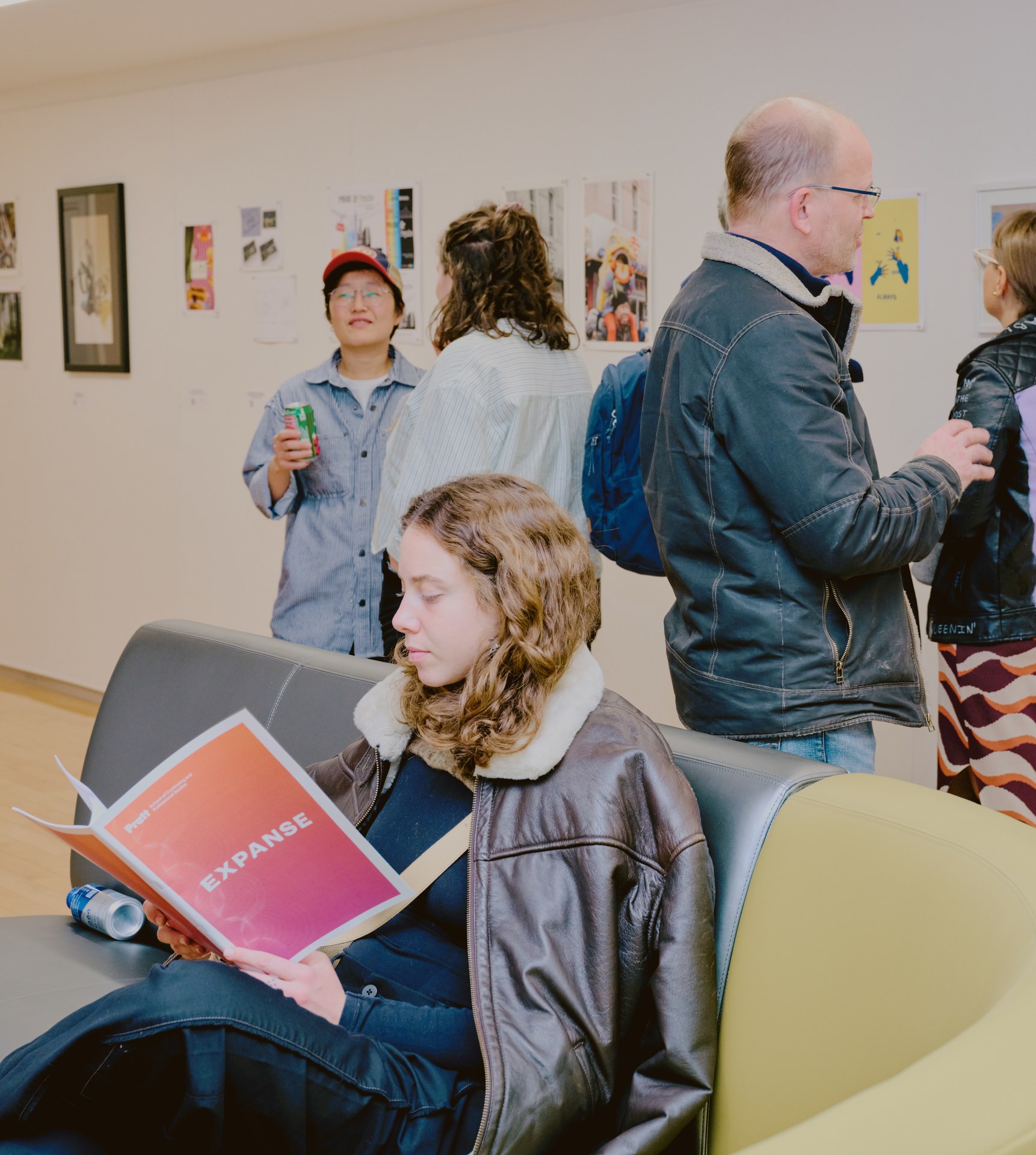 Visitor reading the exhibition catalog at Fall 2026 Expanse Exhibition open house while others mingle near artwork. Photo by Todd Miller.
