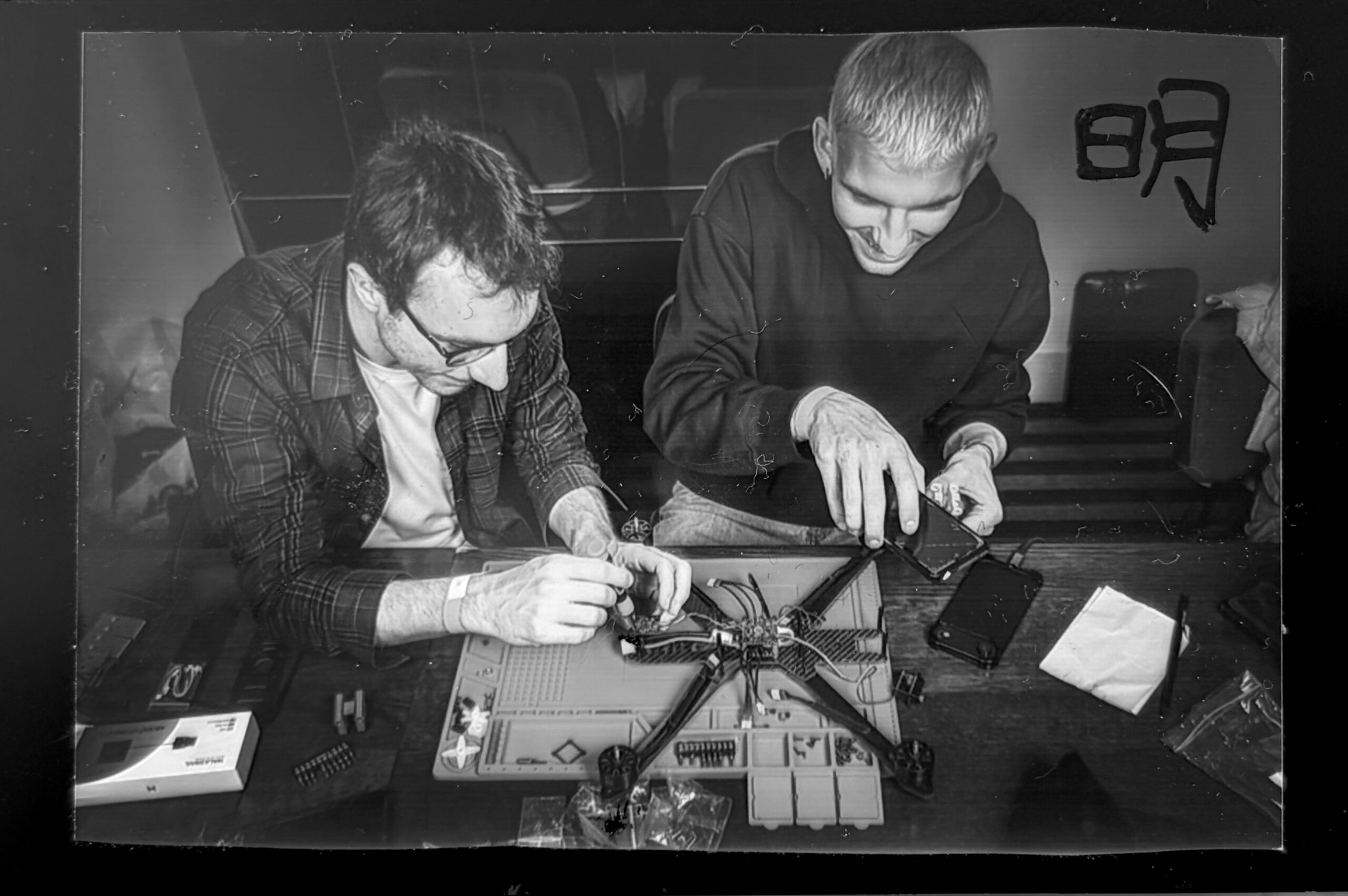 A black and white photo of alum Sebastian Roda and a collaborator working on a partially constructed dronecopter.