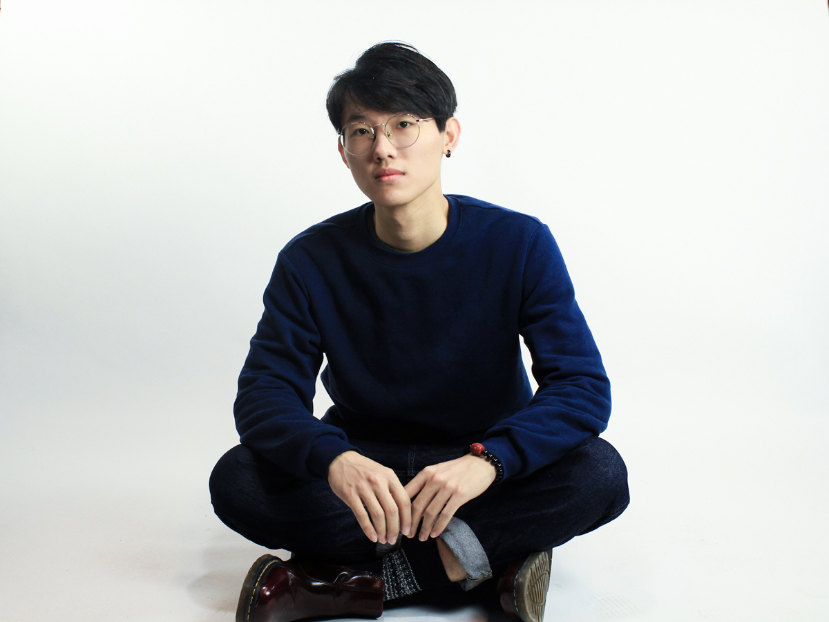 A photograph of Yaokun Wu sitting crosslegged on the floor.