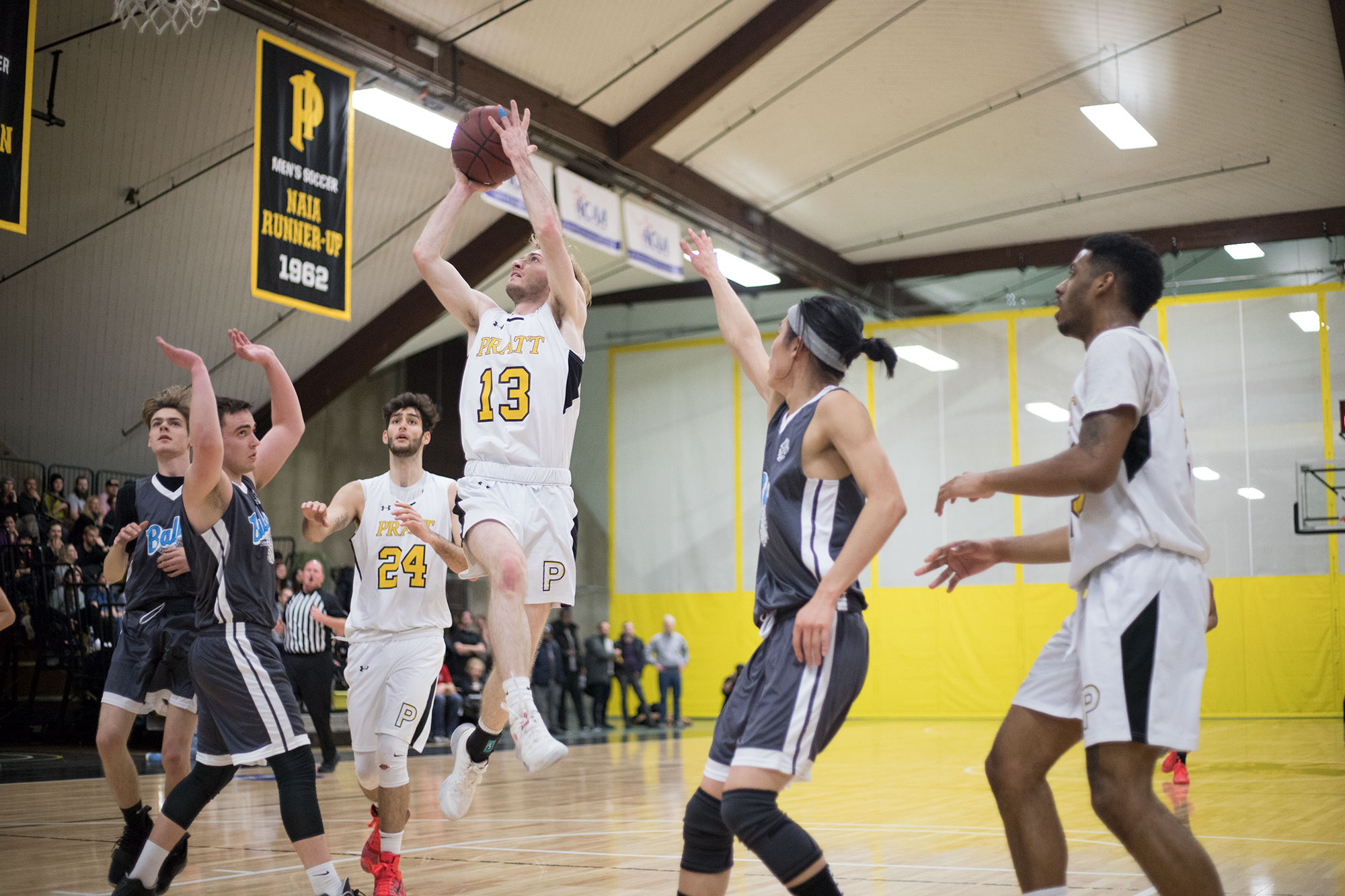 Cannoneer, Griffen Levine (#13), takes a jump shot over RISD defenders.